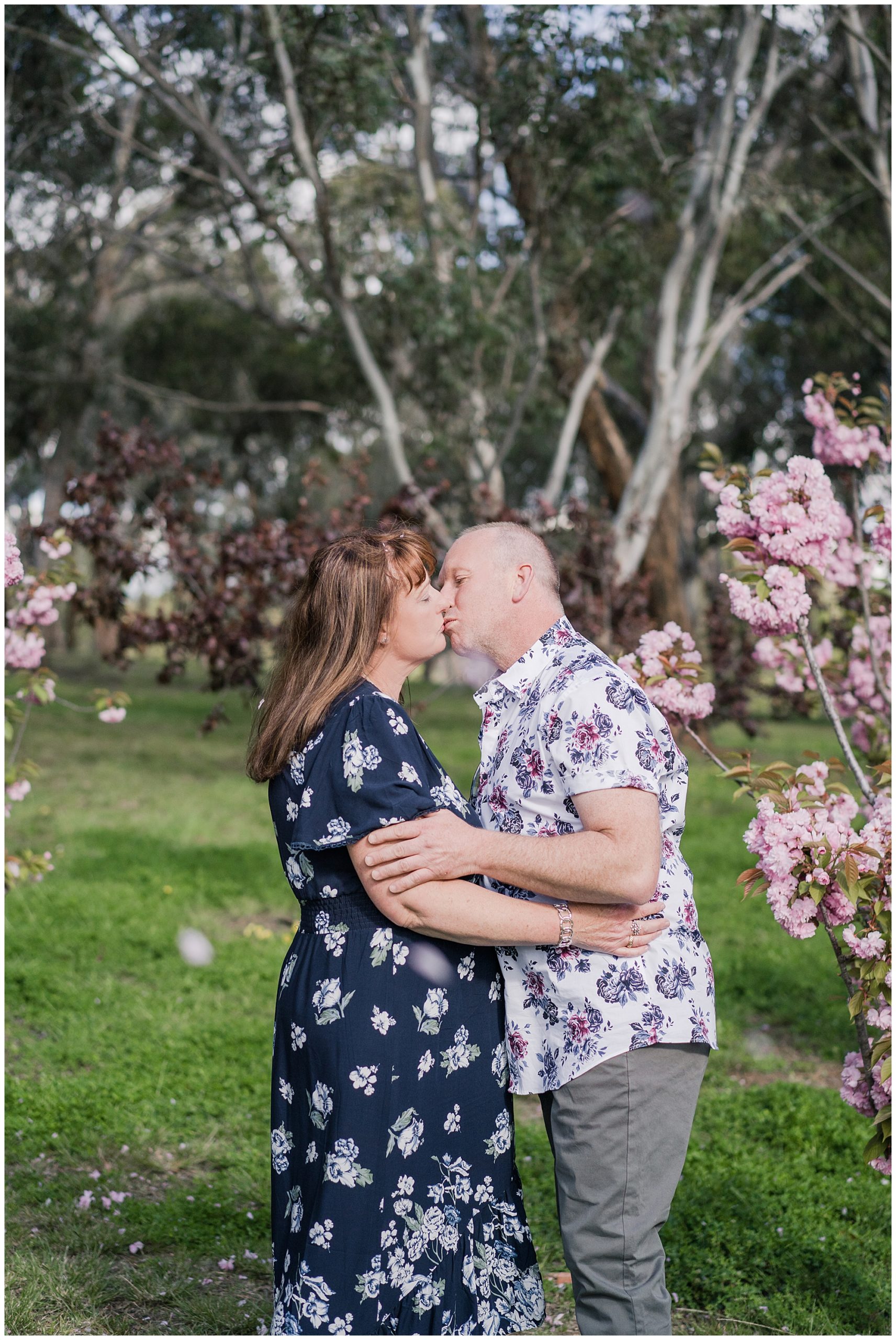 Couple kissing in the middle of pink flowers