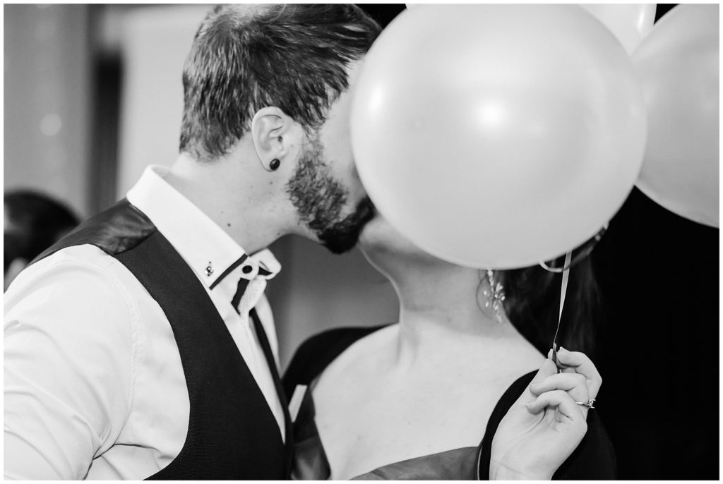Couple kissing behind a baloon