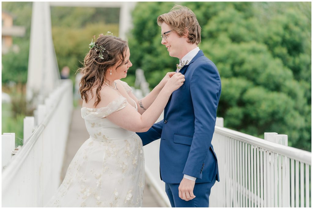 Bride helping her groom with his boutonniere | Wedding photographer