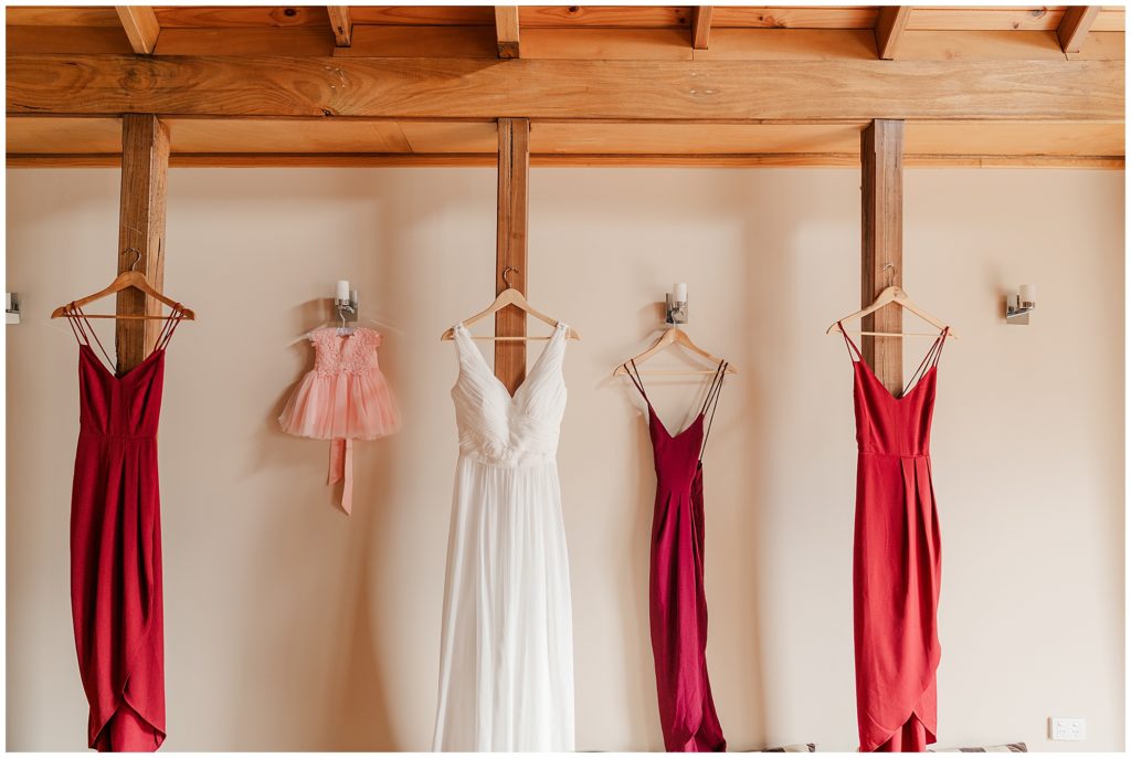 Red bridesmaids dresses hanging next to the beautiful wedding dress